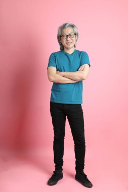 Pembe arka planda duran kıdemli Asyalı adam..