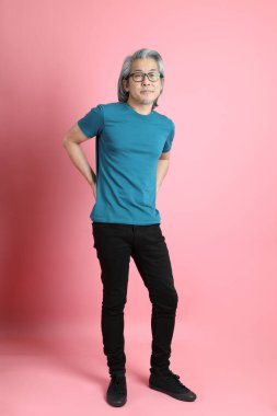 Pembe arka planda duran kıdemli Asyalı adam..