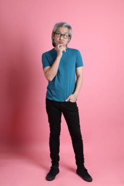 Pembe arka planda duran kıdemli Asyalı adam..