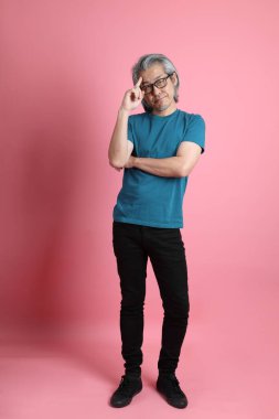 Pembe arka planda duran kıdemli Asyalı adam..