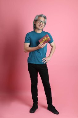 Pembe arka planda duran kıdemli Asyalı adam..