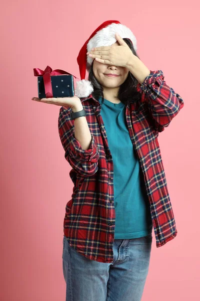 ピンクの背景にサンタの帽子をかぶったアジアの女性 — ストック写真
