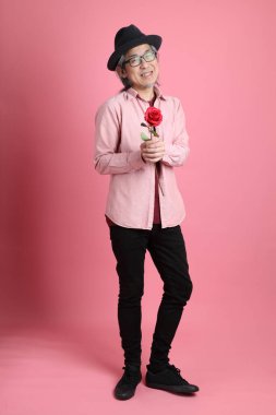 Pembe arka planda duran kıdemli Asyalı adam..