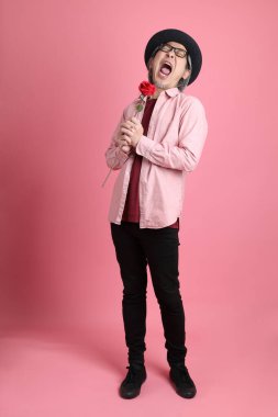 Pembe arka planda duran kıdemli Asyalı adam..