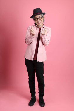 Pembe arka planda duran kıdemli Asyalı adam..