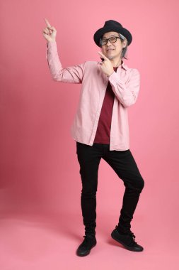 Pembe arka planda duran kıdemli Asyalı adam..