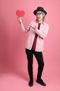 Pembe arka planda duran kıdemli Asyalı adam..