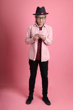 Pembe arka planda duran kıdemli Asyalı adam..