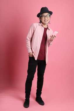 Pembe arka planda duran kıdemli Asyalı adam..