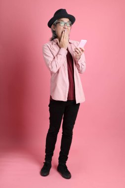 Pembe arka planda duran kıdemli Asyalı adam..