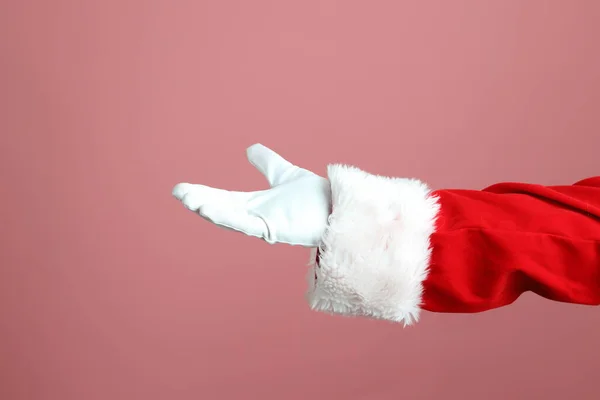 Noel Baba pembe arka planda elini gösteriyor..