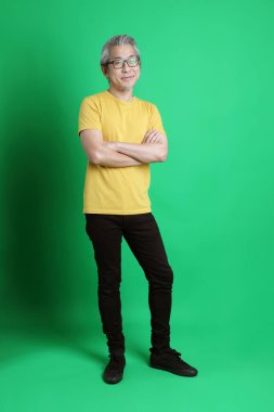 Yeşil arka planda duran uzun gri saçlı yaşlı Asyalı adam..