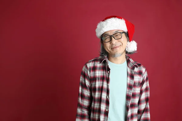Kıdemli Asyalı Adam Kırmızı Arka Planda Duran Noel Baba Şapkalı — Stok fotoğraf