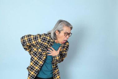 Mavi arka planda duran sarı ekose gömlekli yaşlı Asyalı adam..