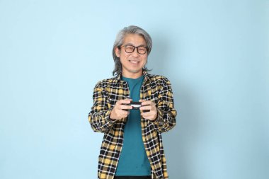 Mavi arka planda duran sarı ekose gömlekli yaşlı Asyalı adam..