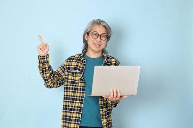 Mavi arka planda duran sarı ekose gömlekli yaşlı Asyalı adam..