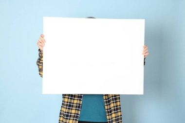 Mavi arka planda duran sarı ekose gömlekli yaşlı Asyalı adam..