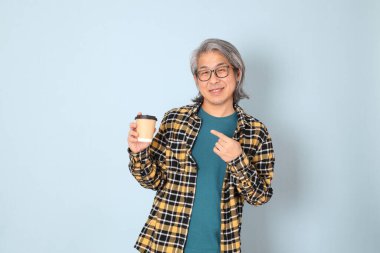 Mavi arka planda duran sarı ekose gömlekli yaşlı Asyalı adam..