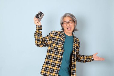 Mavi arka planda duran sarı ekose gömlekli yaşlı Asyalı adam..