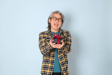 Mavi arka planda duran sarı ekose gömlekli yaşlı Asyalı adam..