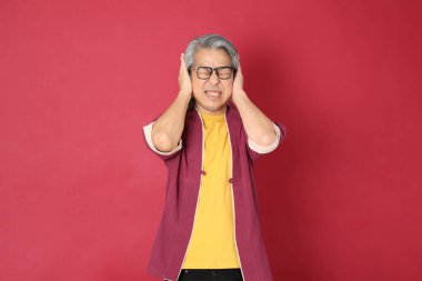 Kırmızı arka planda duran geleneksel Çin kıyafeti giyen kıdemli Asyalı adam..