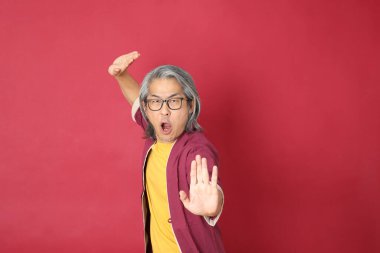 Kırmızı arka planda duran geleneksel Çin kıyafeti giyen kıdemli Asyalı adam..