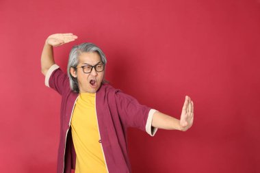 Kırmızı arka planda duran geleneksel Çin kıyafeti giyen kıdemli Asyalı adam..