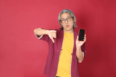 Kırmızı arka planda duran geleneksel Çin kıyafeti giyen kıdemli Asyalı adam..