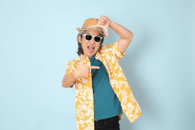 Kıdemli Asyalı yazın giyinen adam mavi arka planda duruyor..