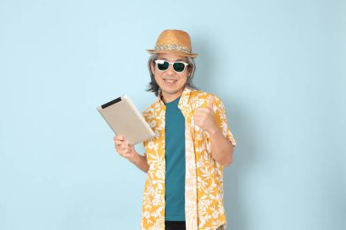 Kıdemli Asyalı yazın giyinen adam mavi arka planda duruyor..