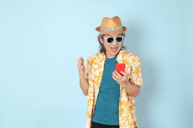 Kıdemli Asyalı yazın giyinen adam mavi arka planda duruyor..