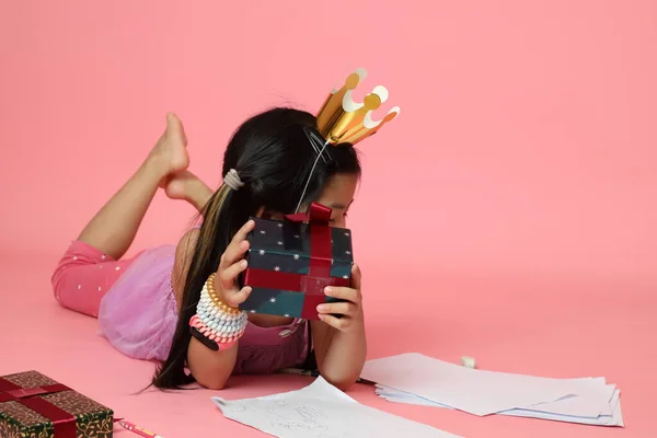 Гарна Азіатська Дівчинка Пише Малюнок Поруч Теперішніми Ящиками Рожевому Фоні — стокове фото