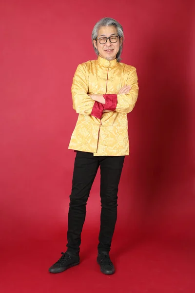 身穿中国传统金装的资深亚洲男子站在红色的背景上 — 图库照片