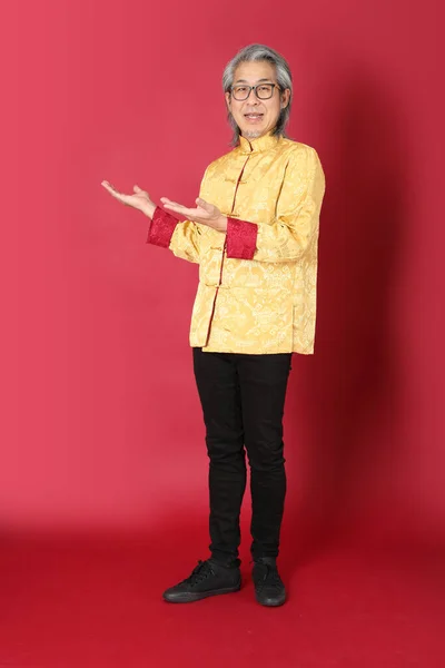 Starszy Azjata Ubrany Tradycyjne Złote Chińskie Sukienki Stojące Czerwonym Tle — Zdjęcie stockowe