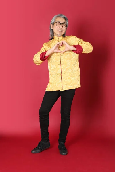 身穿中国传统金装的资深亚洲男子站在红色的背景上 — 图库照片