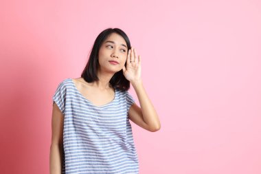 Pembe arka planda duran mavi gömlekli melez kadın..