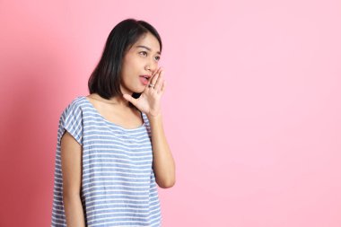 Pembe arka planda duran mavi gömlekli melez kadın..