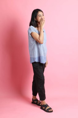 Pembe arka planda duran mavi gömlekli melez kadın..