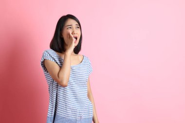 Pembe arka planda duran mavi gömlekli melez kadın..