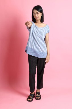 Pembe arka planda duran mavi gömlekli melez kadın..