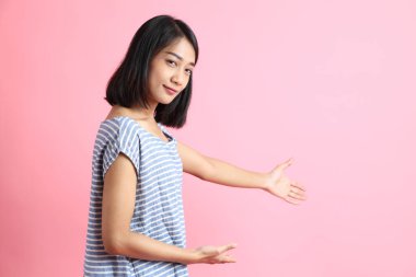 Pembe arka planda duran mavi gömlekli melez kadın..