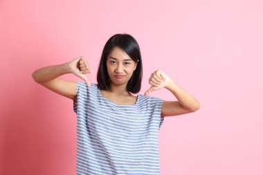 Pembe arka planda duran mavi gömlekli melez kadın..