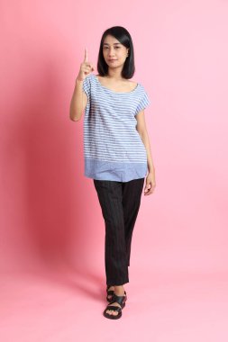 Pembe arka planda duran mavi gömlekli melez kadın..