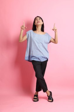 Pembe arka planda duran mavi gömlekli melez kadın..