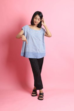 Pembe arka planda duran mavi gömlekli melez kadın..