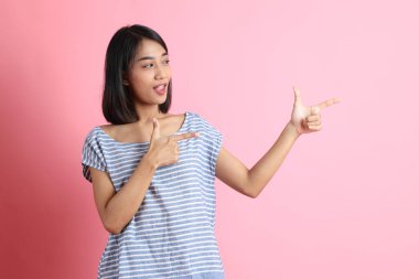 Pembe arka planda duran mavi gömlekli melez kadın..