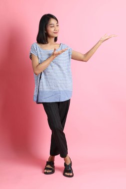 Pembe arka planda duran mavi gömlekli melez kadın..