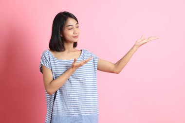 Pembe arka planda duran mavi gömlekli melez kadın..