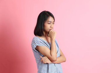 Pembe arka planda duran mavi gömlekli melez kadın..