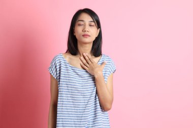 Pembe arka planda duran mavi gömlekli melez kadın..